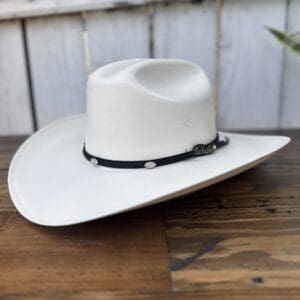 A white cowboy hat sitting on top of a wooden table.