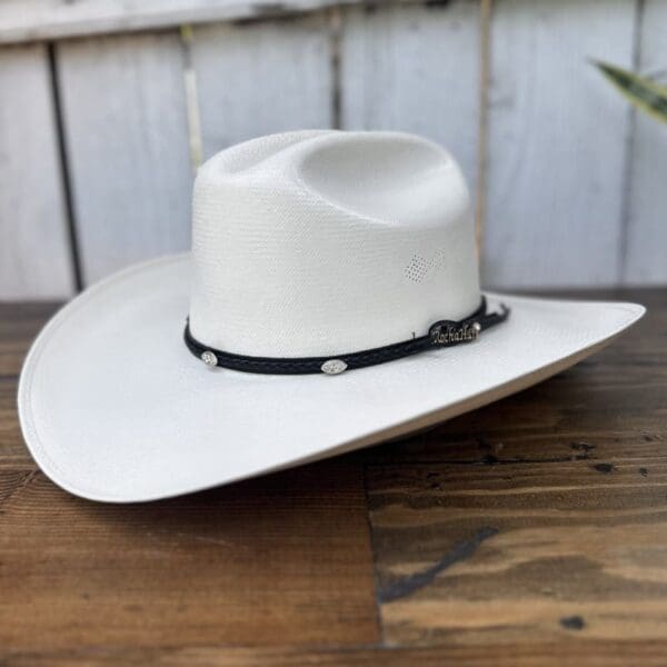 A white cowboy hat sitting on top of a wooden table.