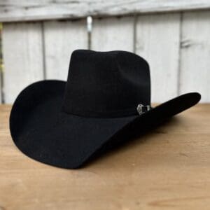 A black cowboy hat sitting on top of a wooden table.