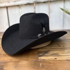 A black cowboy hat sitting on top of a wooden table.