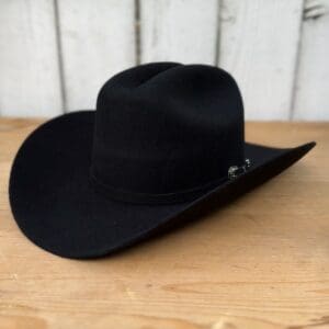 A black cowboy hat sitting on top of a wooden table.