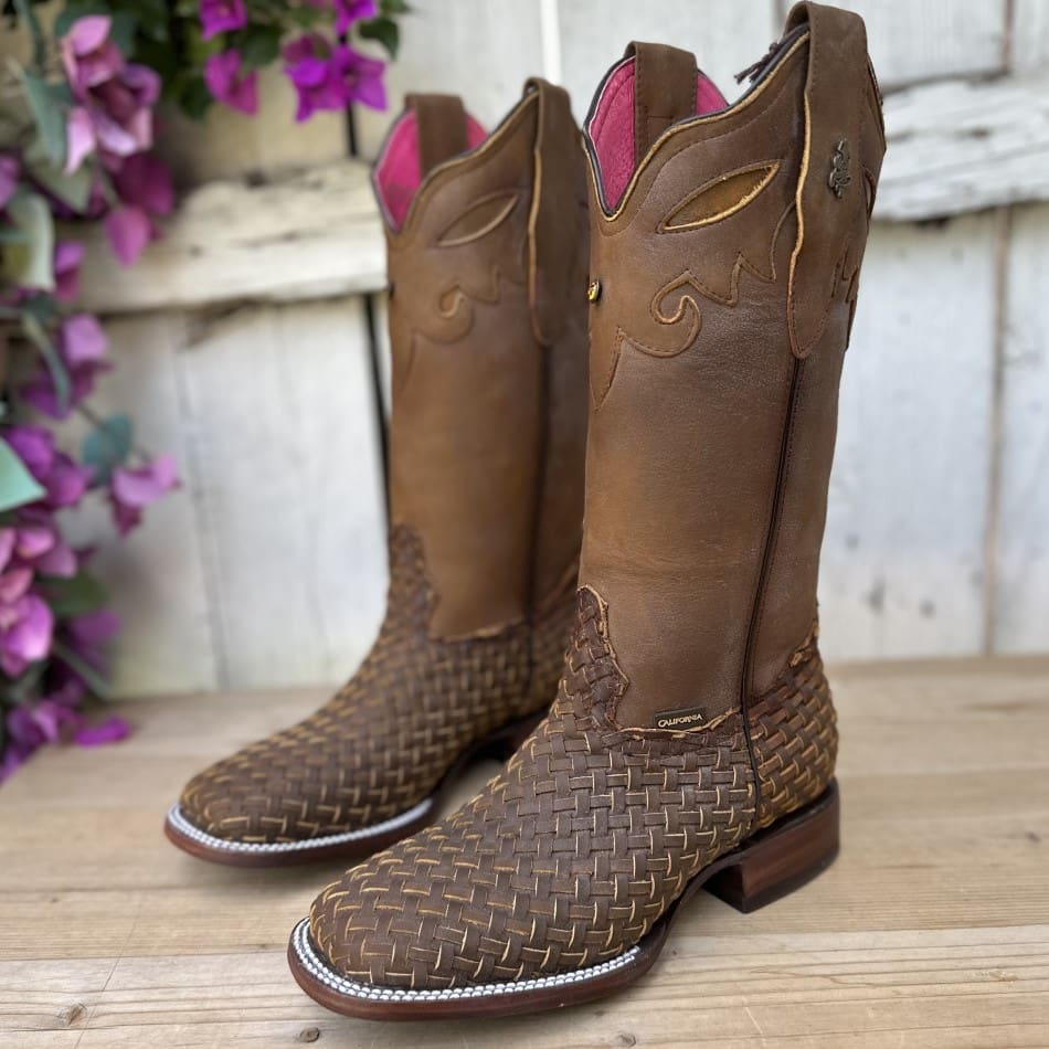 A pair of brown cowboy boots sitting on top of a wooden table.