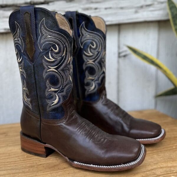 A pair of cowboy boots sitting on top of a wooden table.