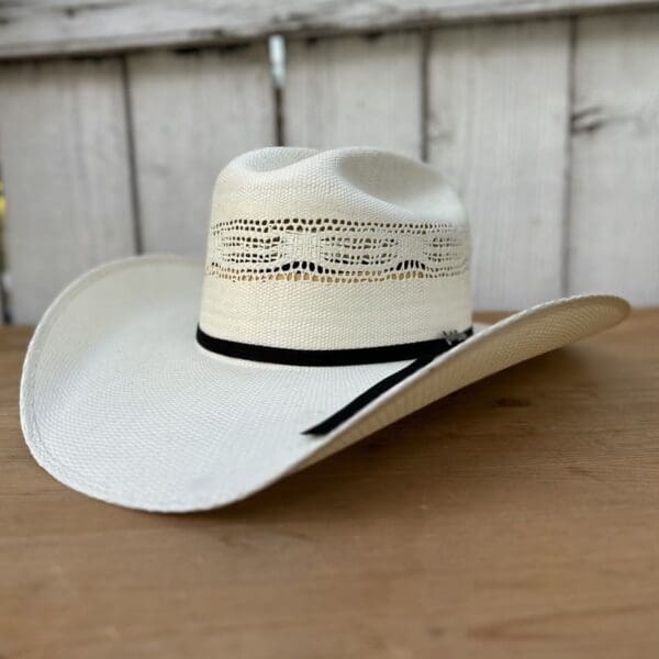 A white cowboy hat sitting on top of a wooden table.