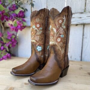 A pair of brown cowboy boots sitting on top of a wooden table.