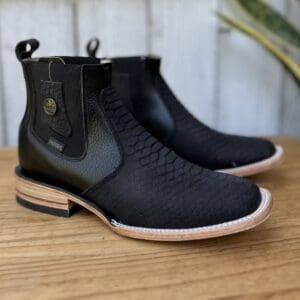 A pair of black boots sitting on top of a wooden table.