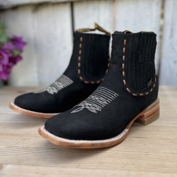 A pair of black boots sitting on top of a wooden floor.