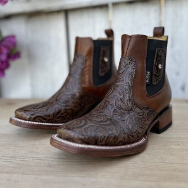 A pair of brown boots sitting on top of a wooden table.