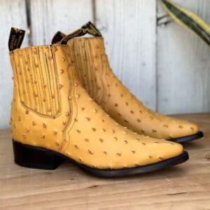 A pair of yellow ostrich skin boots on the ground.