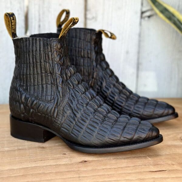 A pair of black boots sitting on top of a wooden table.