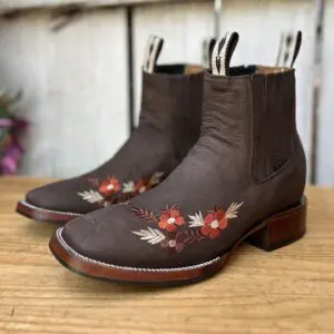 A pair of brown boots with flowers on them.