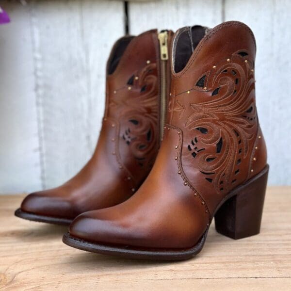 A pair of brown boots sitting on top of a wooden table.