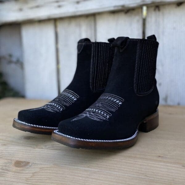 A pair of black boots sitting on top of a wooden table.