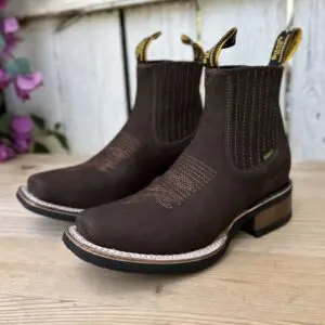 A pair of brown boots sitting on top of a wooden floor.