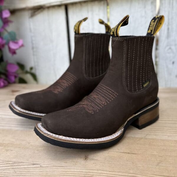 A pair of brown boots sitting on top of a wooden floor.