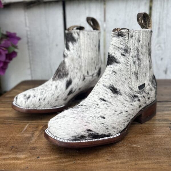 A pair of white and black boots on top of a wooden table.