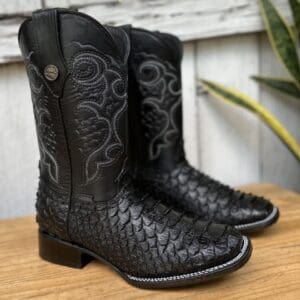 A pair of black cowboy boots sitting on top of a wooden table.