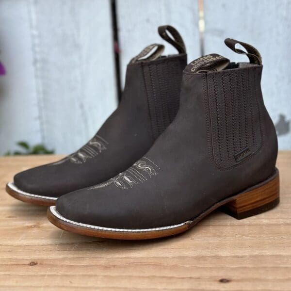 A pair of black boots sitting on top of a wooden table.