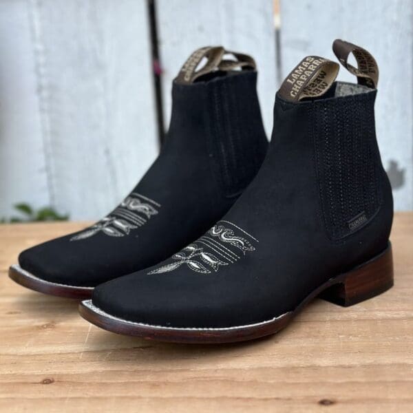 A pair of black boots sitting on top of a wooden table.