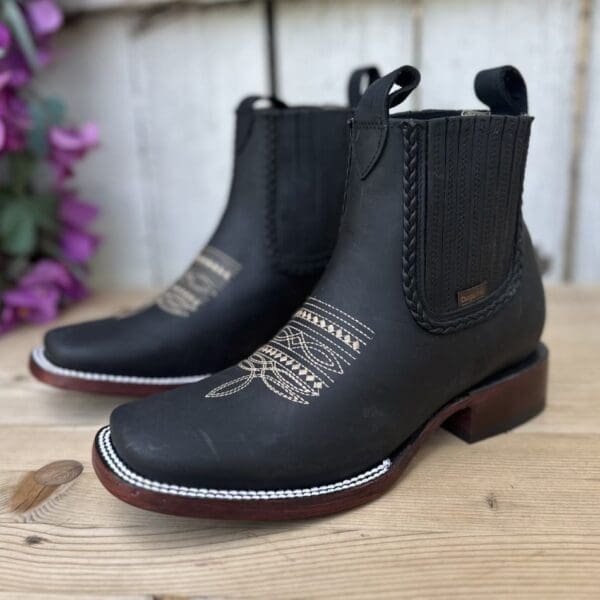 A pair of black boots sitting on top of a wooden table.