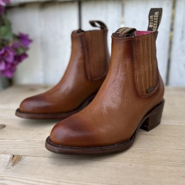 A pair of brown boots sitting on top of a wooden table.