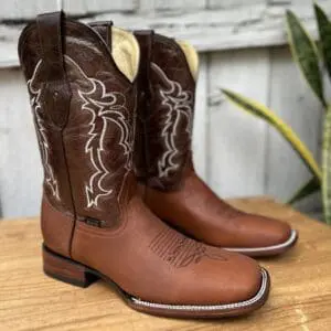 A pair of brown cowboy boots sitting on top of a wooden table.