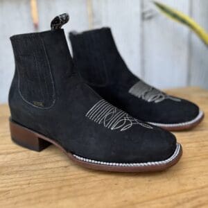 A pair of black boots sitting on top of a wooden table.