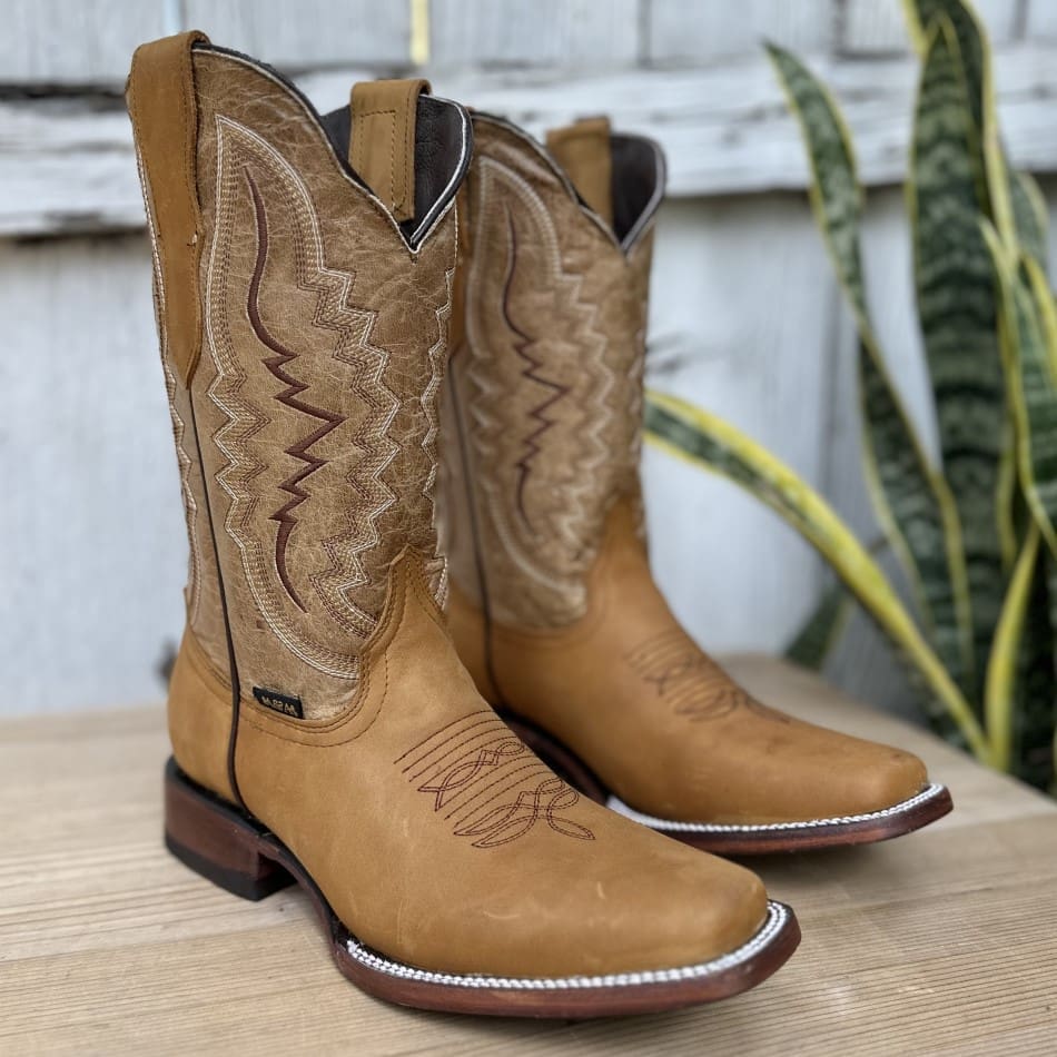 A pair of cowboy boots sitting on top of a wooden table.