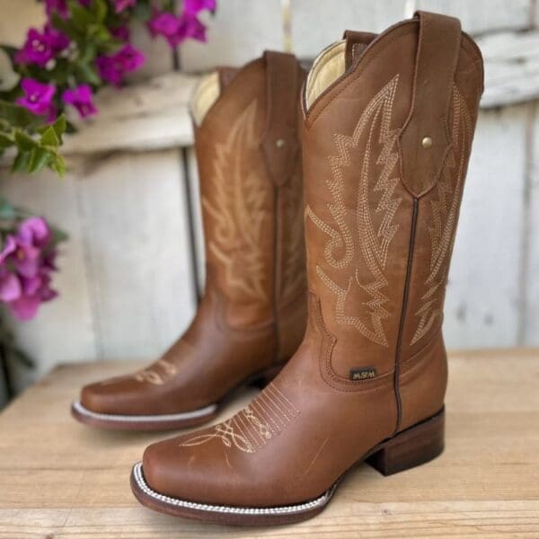 A pair of brown cowboy boots sitting on top of a wooden table.