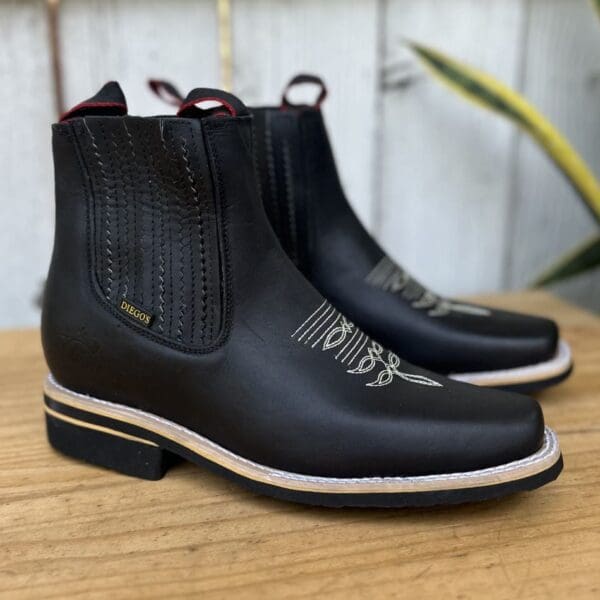 A pair of black boots sitting on top of a wooden table.