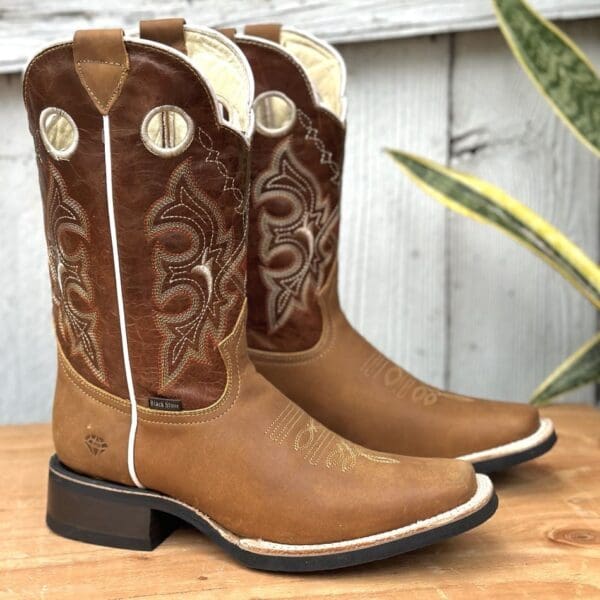 A pair of cowboy boots sitting on top of a wooden table.