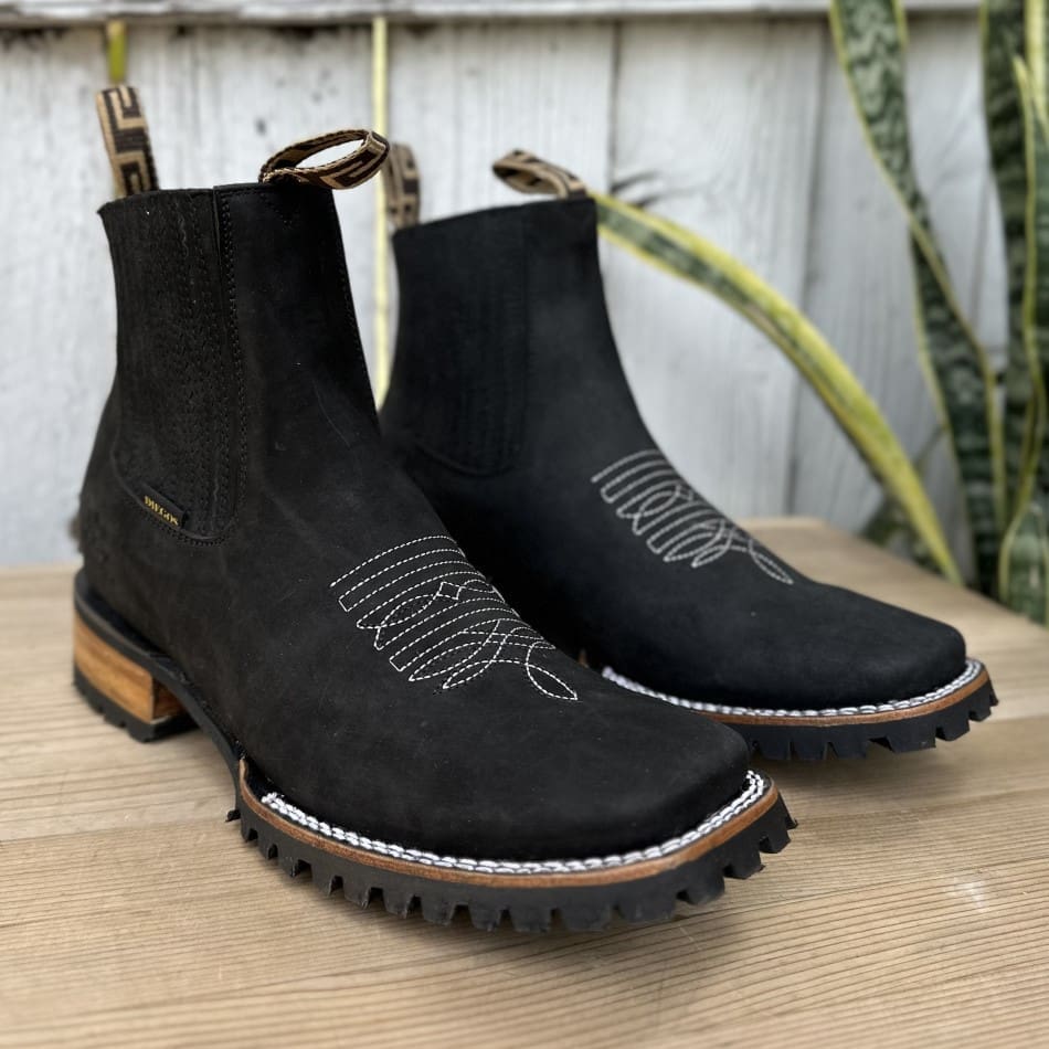 A pair of black boots sitting on top of a wooden table.