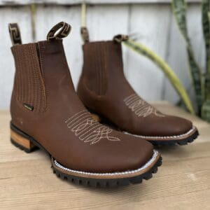 A pair of brown boots sitting on top of a wooden table.