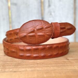 A brown leather belt with a carved design on it.