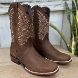 A pair of brown cowboy boots sitting on top of a table.