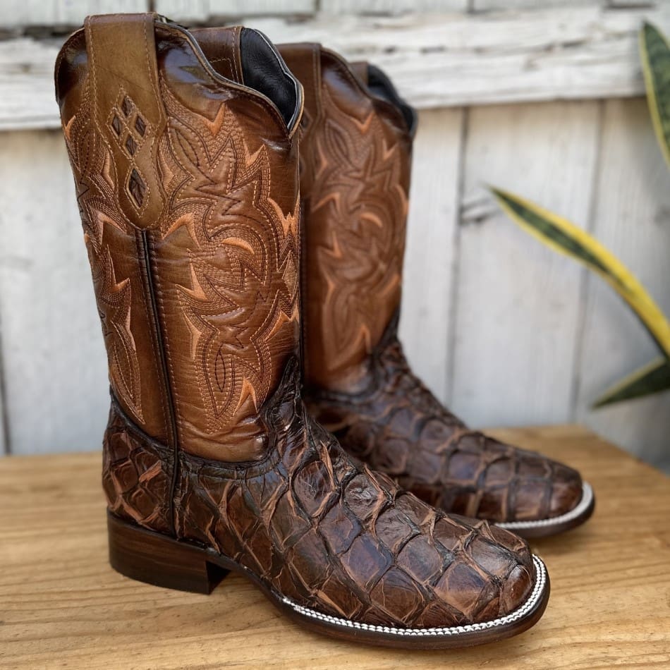 A pair of cowboy boots sitting on top of a wooden table.