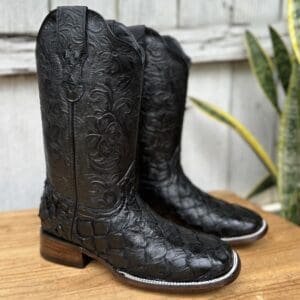 A pair of black cowboy boots sitting on top of a wooden table.