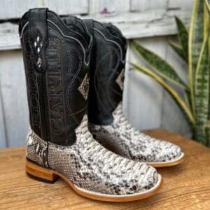 A pair of snake skin boots sitting on top of a wooden table.