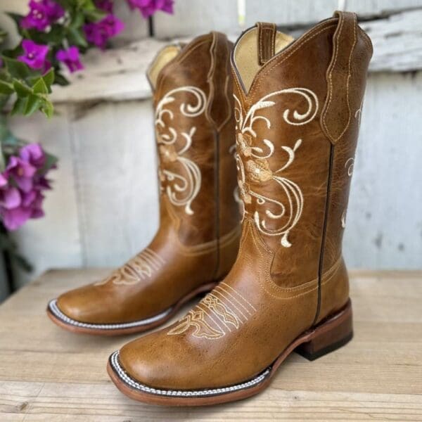 A pair of brown cowboy boots sitting on top of a wooden table.