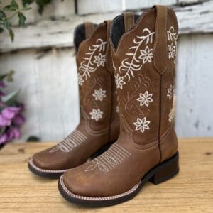 A pair of brown cowboy boots sitting on top of a wooden table.