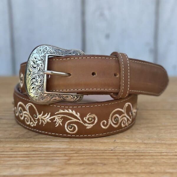 A brown belt with white flowers and a silver buckle