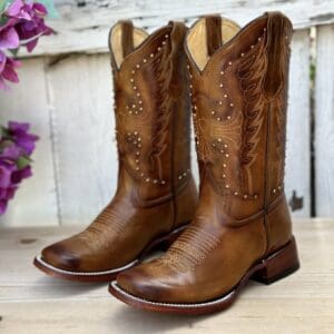 A pair of brown cowboy boots sitting on top of a wooden table.