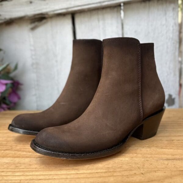 A pair of brown boots sitting on top of a wooden table.