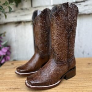 A pair of brown cowboy boots sitting on top of a wooden table.