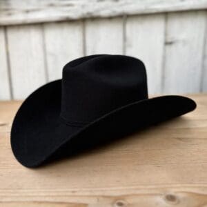 A black cowboy hat sitting on top of a wooden table.