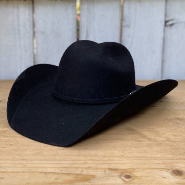 A black cowboy hat sitting on top of a wooden table.