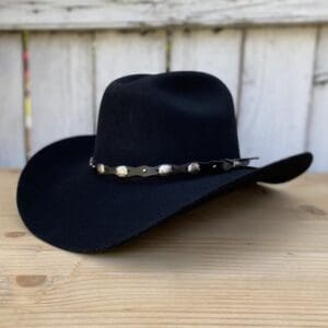 A black cowboy hat sitting on top of a wooden table.