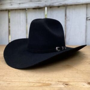 A black cowboy hat sitting on top of a wooden table.