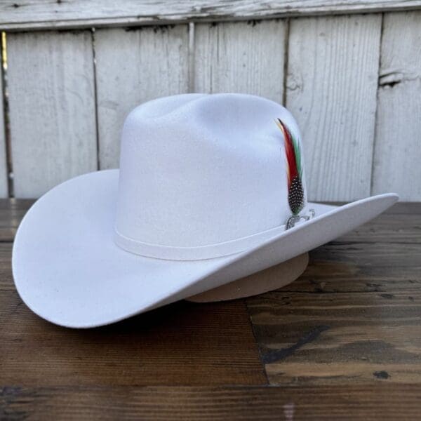 A white cowboy hat sitting on top of a wooden table.